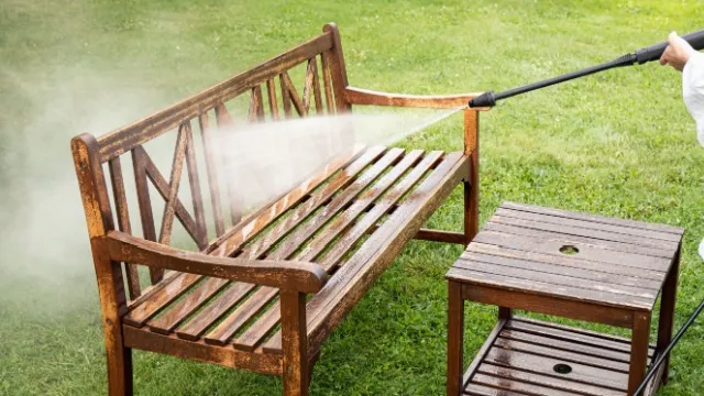 man pressure washing wooden garden bench
