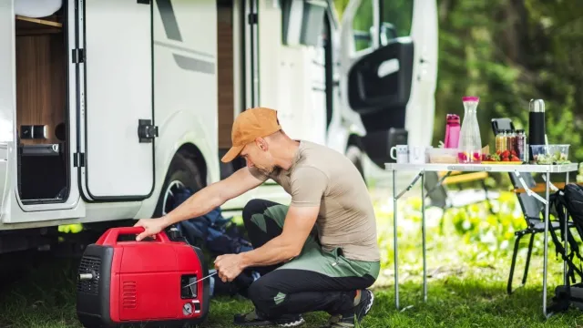 man starts generator in front of camper