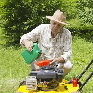 man pours oil into a lawnmower