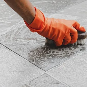 hand in glove brushes tile floor
