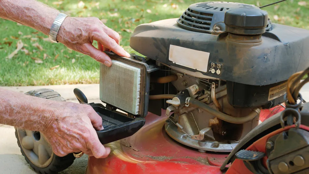 man replaces lawn mower air filter