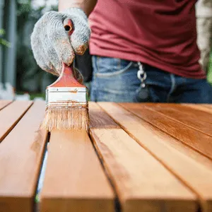 man beitst houten tuintafel